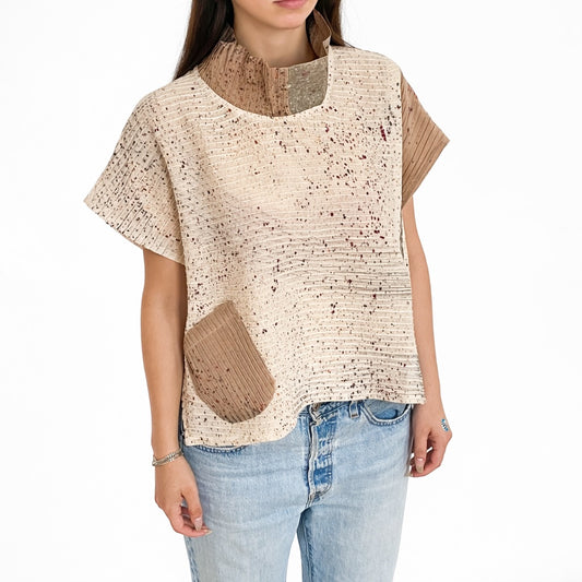 Woman wearing a beige and brown patterned top with denim jeans on a white background